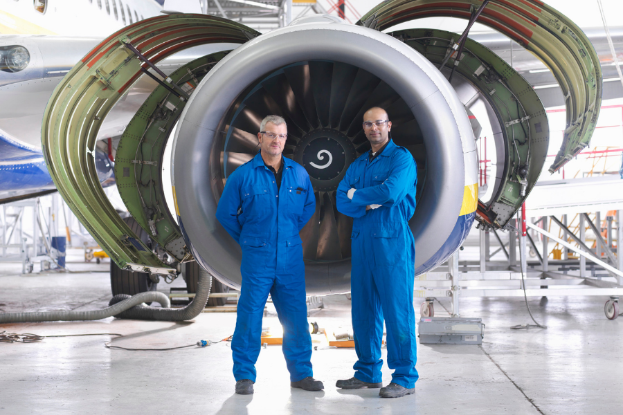 Machine engineers posing in front of aircraft manifacturing